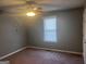 A simple bedroom featuring a ceiling fan, one window, and brown carpeted floors at 1694 Social Circle Fairplay Rd, Social Circle, GA 30025