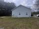 Side exterior of a blue home with a lawn, showcasing the home's siding and foundation at 1694 Social Circle Fairplay Rd, Social Circle, GA 30025