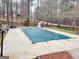 Backyard with a pool featuring a safety cover surrounded by trees and greenery at 3213 Sweetbriar Dr, Villa Rica, GA 30180