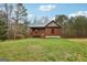 Charming log cabin with a green metal roof and shed nestled in a serene wooded environment with a sprawling lawn at 1266 Martin Mill Rd, Moreland, GA 30259