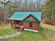 Charming log cabin with a green roof, featuring a cozy deck and scenic surroundings, blending rustic charm with nature at 1266 Martin Mill Rd, Moreland, GA 30259