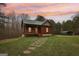 Inviting log cabin with stone path, carport, and lush lawn under a colorful sunset sky at 1266 Martin Mill Rd, Moreland, GA 30259