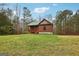 Quaint log cabin with a green metal roof nestled in a peaceful wooded setting with a well-manicured lawn at 1266 Martin Mill Rd, Moreland, GA 30259