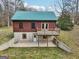 Rear view of cabin with a walk-out basement and a wood deck, set against a green grassy lawn at 1266 Martin Mill Rd, Moreland, GA 30259
