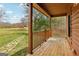 Covered porch with wood railings and flooring overlooking a lush green landscape with stone path at 1266 Martin Mill Rd, Moreland, GA 30259
