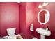 Stylish half bathroom features a round mirror, pedestal sink, and striking red walls at 408 Tomahawk Trl, Mcdonough, GA 30252