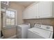 Functional laundry room with ample storage cabinets and a bright window for natural light at 408 Tomahawk Trl, Mcdonough, GA 30252