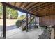 Cozy covered patio with wooden beams, brick accent wall, and stairs to the backyard, perfect for outdoor relaxation at 408 Tomahawk Trl, Mcdonough, GA 30252