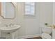 Stylish half bathroom features a pedestal sink, ornate mirror, and tiled floors, adding elegance to the space at 1133 Astoria Ln, Peachtree City, GA 30269