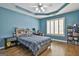 Blue bedroom features a trey ceiling, ceiling fan, and window with white shutters at 1133 Astoria Ln, Peachtree City, GA 30269
