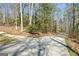 View of concrete driveway leading to home through a wooded area on a sunny day at 150 Gill Ln, Stockbridge, GA 30281