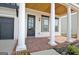 Inviting front porch with brick flooring, classic white pillars, and a wood ceiling creates a warm and welcoming entryway at 446 Bandon Way, Peachtree City, GA 30269