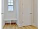 Hallway nook with a small window, white storage bench, white door, and light hardwood floors at 446 Bandon Way, Peachtree City, GA 30269