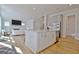 White kitchen island with stainless appliances, and open layout to the living room with fireplace, light wood floors at 446 Bandon Way, Peachtree City, GA 30269