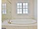 Bright soaking tub surrounded by marble and featuring a sunny window at 446 Bandon Way, Peachtree City, GA 30269