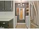 Bright laundry room featuring wooden shelves, built-in ironing board, washer, and stainless steel refrigerator at 1120 Minix Rd, Sharpsburg, GA 30277