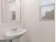 Bathroom featuring a pedestal sink, a round mirror, and a window with white blinds at 464 Reflection Dr # 22, Stockbridge, GA 30281