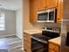 Well-lit kitchen featuring stainless steel appliances, wood cabinets, and laminate flooring at 75 Heatherstone Way, Covington, GA 30016