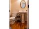 Classic half bathroom showcases a pedestal sink, an oval mirror, and sleek wood floors at 9989 Village South Dr, Douglasville, GA 30135