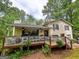 Charming home featuring a cozy front porch with ceiling fans, surrounded by lush trees and a well-manicured yard at 1972 Cox Dr, Austell, GA 30168