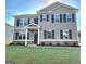 Two-story home with gray siding, black shutters, well-manicured lawn, and covered front entrance at 201 Friendship Oak Way, Hampton, GA 30228