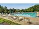 Large community swimming pool, featuring lounge chairs, an umbrella table, and a clear blue sky at 305 Worthing Lane, Mcdonough, GA 30253