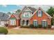 Charming two-story red brick home with green shutters and a well-manicured front yard at 2510 Shoreline Pkwy, Villa Rica, GA 30180