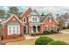 Charming two-story red brick home with green shutters and a well-manicured front yard at 2510 Shoreline Pkwy, Villa Rica, GA 30180