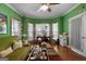 Cozy living room with green walls, wood floors, and bright windows with floral curtains at 1561 Aiken Chafin Ln, Mcdonough, GA 30252