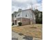 View of the townhome from the side, showing the lawn and a young tree at 1463 River Stone Trce, Conyers, GA 30012
