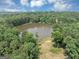 Aerial view of a tree-lined pond with a home nestled in the background at 4233 Sandstone Shores Dr, Stonecrest, GA 30038