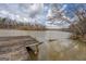 Scenic lake view featuring a wooden dock and calm water against a cloudy sky and wooded shoreline at 650 Malcom Rd, Covington, GA 30014