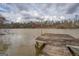 Picturesque lake view with a wooden dock, calm water reflecting the cloudy sky, and wooded surroundings at 650 Malcom Rd, Covington, GA 30014