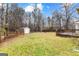 Large backyard with a grassy area, trees, fence, and a storage shed offers a private outdoor space at 134 Floresta Dr, Mcdonough, GA 30252