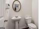 Small half bathroom with pedestal sink, toilet, and an oval mirror at 903 Hollytree Pl, Acworth, GA 30102