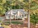 Aerial view of a single-story house with a chimney, lush landscaping, and a driveway, framed by trees at 1300 Lakehaven Pkwy, Mcdonough, GA 30253