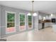 Bright kitchen features white cabinets, a chandelier, large windows and an adjacent dining area with access to the deck at 1300 Lakehaven Pkwy, Mcdonough, GA 30253