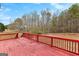 Back deck with red flooring, wooden railings, and view of the wooded backyard at 510 Virginia Highlands, Fayetteville, GA 30215