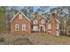 Inviting red brick home featuring a classic architectural design with white trim, arched windows, and a covered entryway at 165 Standing Oak Pl, Fayetteville, GA 30214