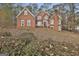 Attractive two-story brick home with mature landscaping, featuring a mix of trees, bushes, and greenery at 165 Standing Oak Pl, Fayetteville, GA 30214