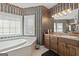Bright bathroom showcasing a soaking tub and vanity, accented by striped wallpaper and ample natural light at 7395 Old Rico Rd., Chattahoochee Hills, GA 30268