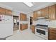 Functional kitchen with white appliances, gas range, and wood cabinets, open to other living spaces at 7395 Old Rico Rd., Chattahoochee Hills, GA 30268