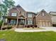 Beautiful brick home with covered porch, manicured lawn, and attached two car garage at 1521 Ashbury Park Dr, Hoschton, GA 30548