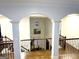 Hallway with hardwood floors, white pillars, and black iron railings overlooking the foyer at 1521 Ashbury Park Dr, Hoschton, GA 30548