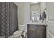 Cozy bathroom featuring a vanity with dark cabinets and a marble countertop, next to a toilet and shower with patterned curtain at 130 Brooks Cir, Hampton, GA 30228