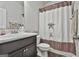 Bathroom with a vanity featuring dark cabinets and a marble countertop, next to a toilet and shower with patterned curtain at 130 Brooks Cir, Hampton, GA 30228