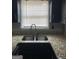 Close-up of a kitchen sink with a window view, granite countertops, and black cabinets at 4477 Golf Vista Cir, Decatur, GA 30035