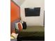 Well-lit bedroom with an orange accent wall and mounted television above an upholstered bed at 7193 Cavender Sw Dr, South Fulton, GA 30331