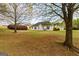 View of the backyard featuring a well-maintained lawn, mature trees, and a charming white house at 628 Morningside Dr, Stockbridge, GA 30281