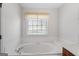 Relaxing bathtub features neutral tile work and a view to outside at 628 Morningside Dr, Stockbridge, GA 30281
